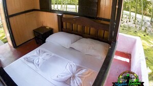 Una cama de madera con ropa de cama blanca y un cabecero, una mesita de noche con una lámpara pequeña y un letrero en la pared con la palabra 'LOVE'.