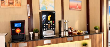 Una recepción con una máquina de café, un quiosco digital y una pared decorativa con cuadros.