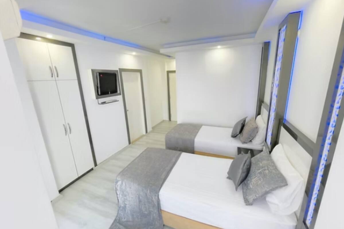 A modern hotel room with two beds, a TV, and a wardrobe.