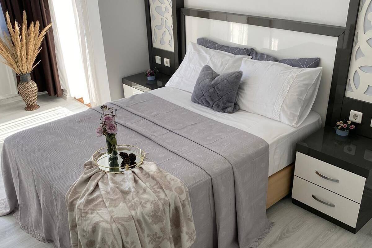 A modern bedroom with a bed, bedside tables, a nightstand, a decorative vase, and a floor lamp.