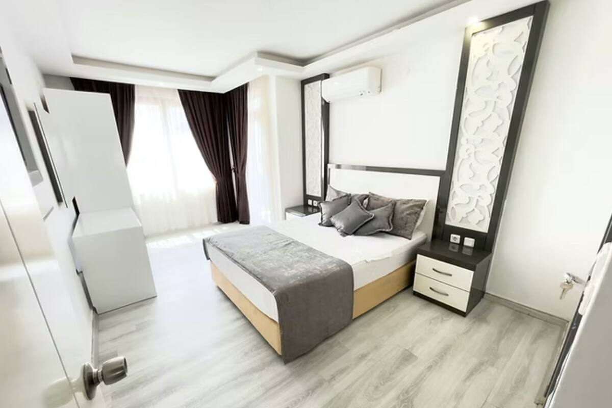 A modern bedroom with a bed, bedside tables, a large mirror, and a wardrobe.