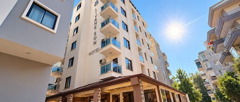 A hotel building with multiple balconies and a covered outdoor seating area.
