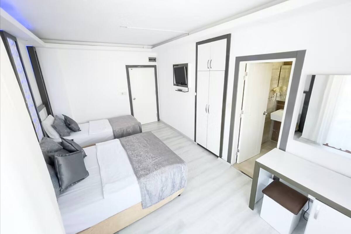 A modern hotel room with a bed, a desk, and a wardrobe.