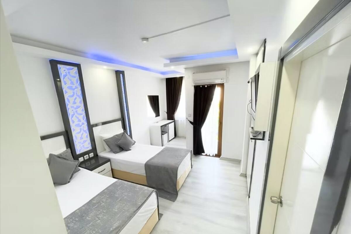 A modern hotel room with two beds, a desk, and a wardrobe.