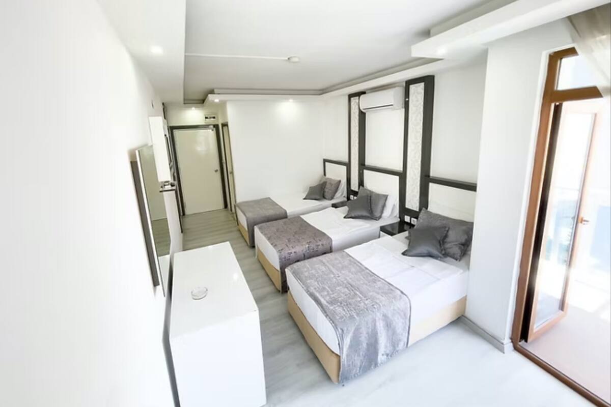 A modern hotel room with two beds, a desk, and a large window.