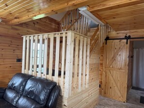 Un interior de madera con una escalera, un sofá de cuero negro y una puerta de madera.
