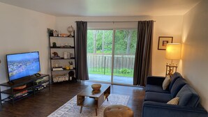 A living room with a TV, a sofa, a coffee table, and a bookshelf. - Affordable and Spacious unit 1 block from the Seattle Light Rail! (Seattle)