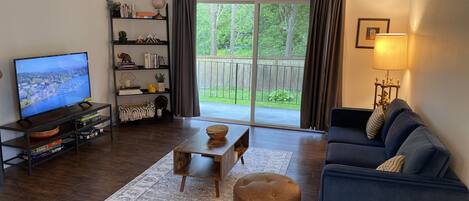 Een woonkamer met een televisie, een bank, een salontafel en een boekenkast.
