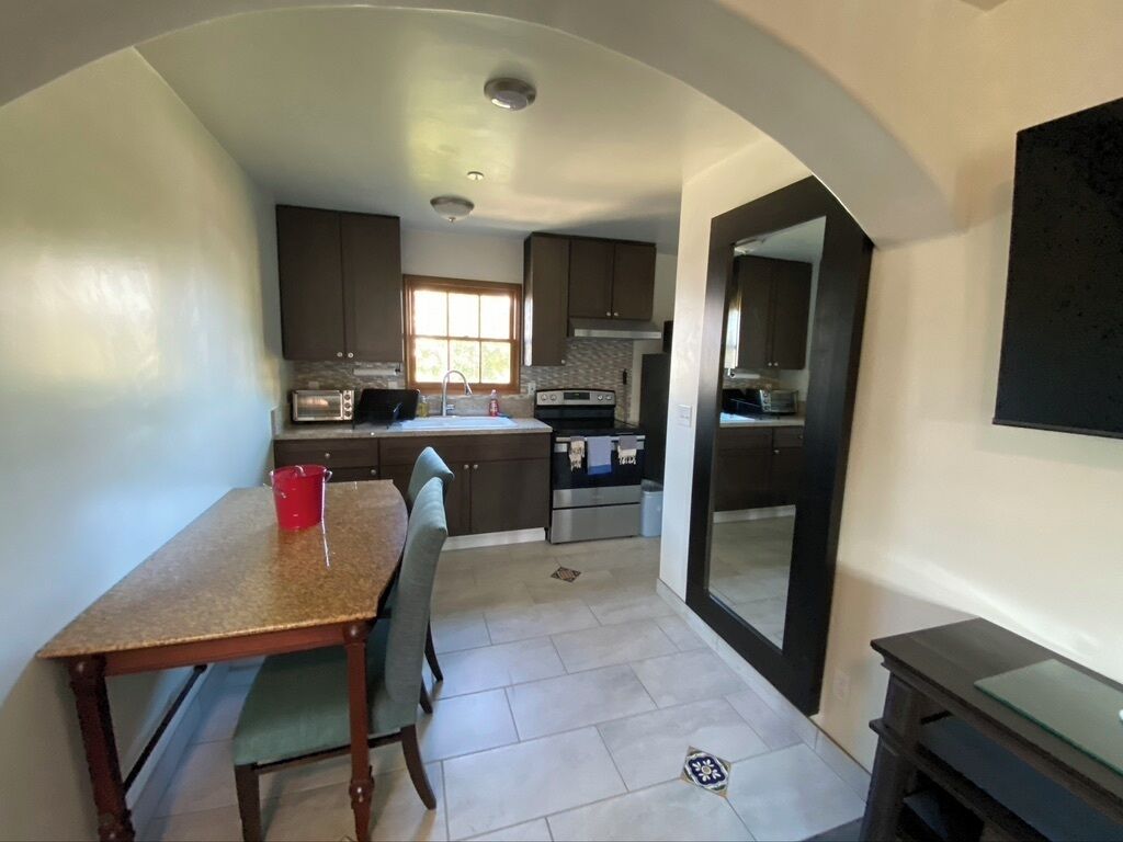 A compact kitchen with dark cabinets, a built-in oven, and a dining area with a table and chairs.