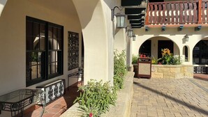 A courtyard with a tiled floor, a glass table, and a planter with flowers. - Tide Pool Villas (Santa Barbara)