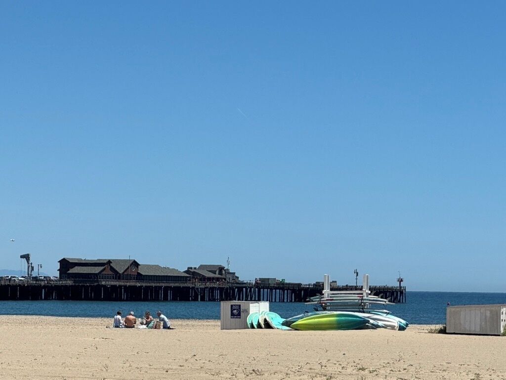 Ein Strand mit einer Mole, einem Gebäude und mehreren Booten.