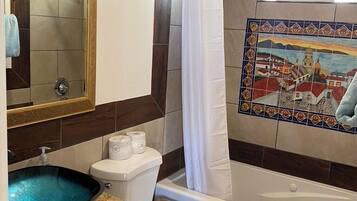 Une salle de bain équipée d’une baignoire, de toilettes, d’un lavabo et d’une douche avec une porte en verre.