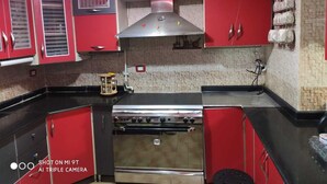 Uma cozinha com armários vermelhos, fogão de aço inoxidável e painel de azulejos.