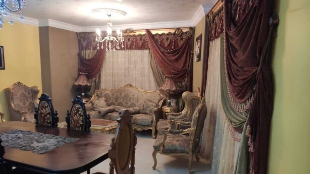 Uma sala de estar tradicional com mobiliário elaborado, um candelabro e cortinas com drapeados.