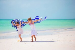Two individuals on a beach with a clear sky and turquoise water. - Steps from the pool and just a 5-minute walk to the beach! 🌴🏖️ (Miramar Beach)