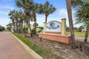 Señal de Gulfwalk con un sendero pavimentado y palmeras.
