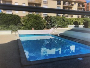 Une piscine avec vue sur un immeuble d’habitation en arrière-plan.
