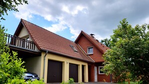 A two-story house with a sloped roof, a balcony on the first floor, and a garage. - Ferienhaus in Idyllischer Dorfrandlage (Gülzow-Prüzen)