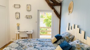 A bedroom with a bed, a desk, and a chair. There is a window with a view of greenery outside.