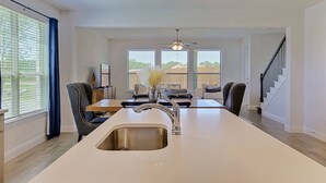 A modern kitchen with a central island, stainless steel sink, and a ceiling fan. - New home, Argyle TX, 4 Bd rooms, 5 bds, 3 Bathrooms, Office, Gameroom, Sleeps 11 (Argyle)
