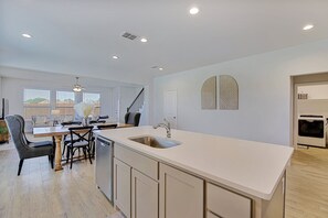 A modern kitchen with a central island, built-in dishwasher, and a large window. - New home, Argyle TX, 4 Bd rooms, 5 bds, 3 Bathrooms, Office, Gameroom, Sleeps 11 (Argyle)