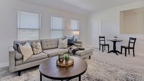 A living room with a grey sofa, two armchairs, a coffee table, and a dining table with chairs. - New home, Argyle TX, 4 Bd rooms, 5 bds, 3 Bathrooms, Office, Gameroom, Sleeps 11 (Argyle)