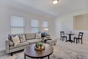 A living room with a grey sofa, two armchairs, a coffee table, and a dining table with chairs. - New home, Argyle TX, 4 Bd rooms, 5 bds, 3 Bathrooms, Office, Gameroom, Sleeps 11 (Argyle)