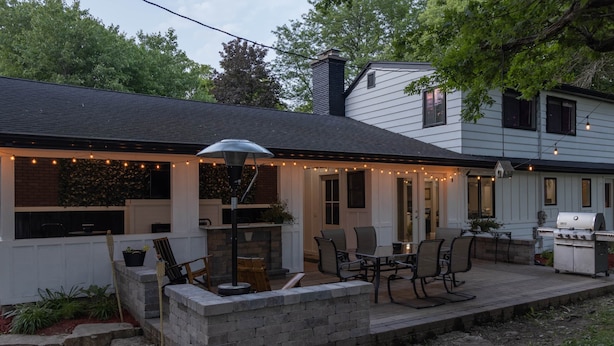 Eine Terrasse mit Sitzgelegenheit im Freien, einem Grill und Lichterketten.