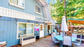 Et blåt hus med terrasse, udendørs siddepladser og et fjernsyn.