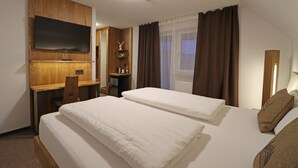 A hotel room with two beds, a desk, a TV, and a window with curtains. - Hotel Kreuz Höhengasthof (Breitnau)