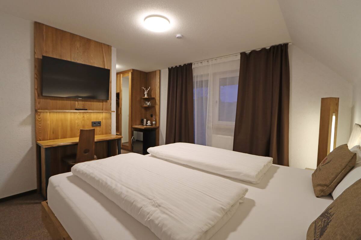 Une chambre d’hôtel avec deux lits, un bureau, une télévision et une fenêtre avec des rideaux.