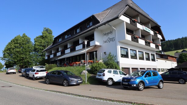 A multi-story hotel with balconies, a parking lot, and a clear blue sky. - Hotel Kreuz Höhengasthof (Breitnau)