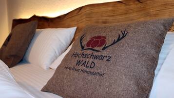A bed with a pillow featuring a logo and text, a wooden headboard, and a textured wall.