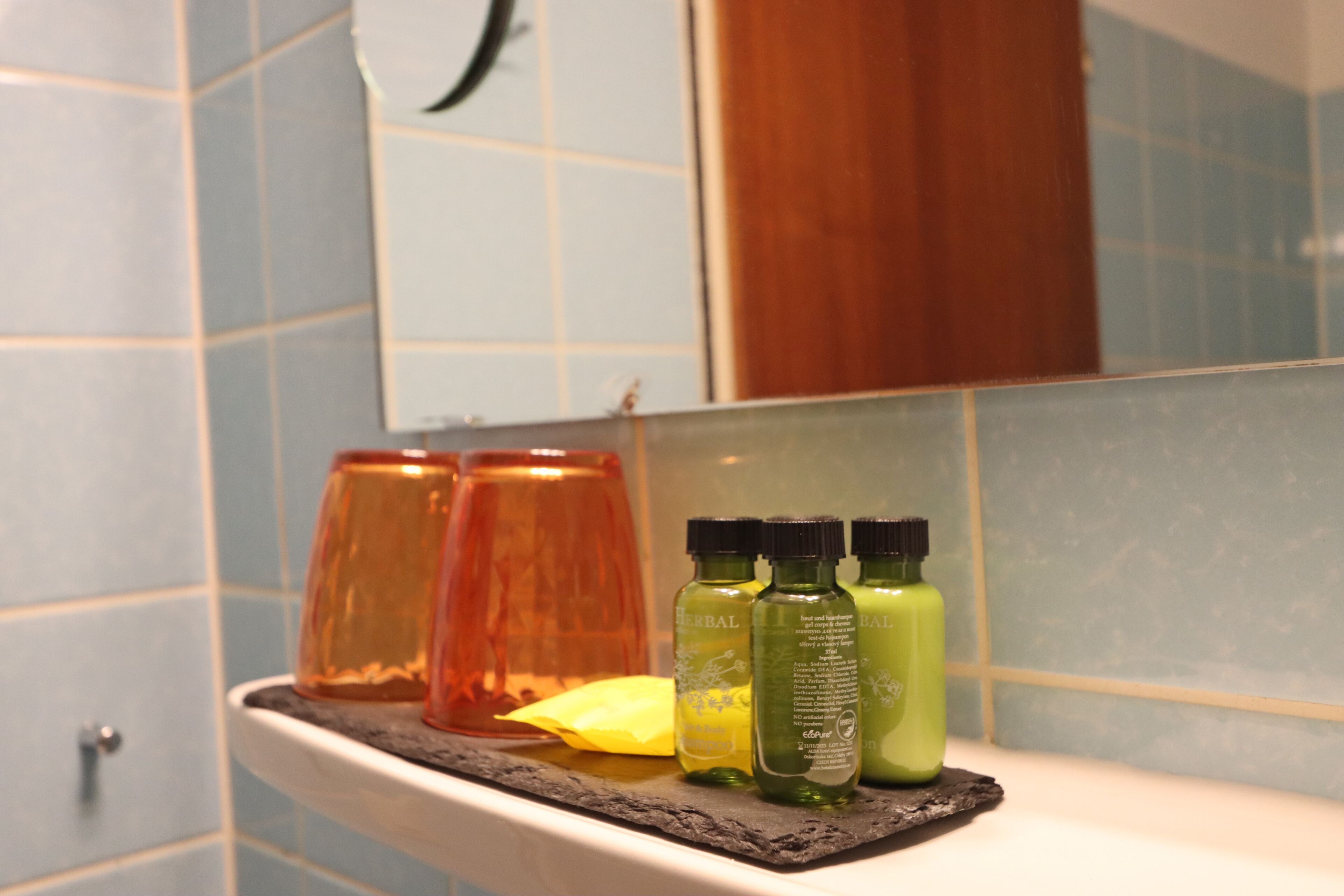A bathroom shelf with three bottles of liquid and a glass jar.
