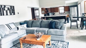 A modern living room with a grey sectional sofa, a wooden coffee table, and a patterned rug.
