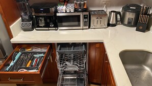 Cozinha equipada com micro-ondas, torradeira, cafeteira e gaveta lava-louças.