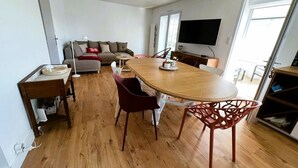 Un vaste espace de vie comprenant une table à manger en bois, des chaises rouges, un canapé et un téléviseur à écran plat.