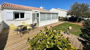 Une maison moderne dotée d’une terrasse en bois, d’un patio vitré et d’un jardin.