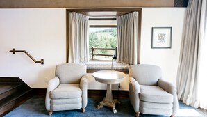 A room with two grey armchairs, a small round table, a window with curtains, a framed picture on the wall, and a wooden staircase. - Sterling One Bedroom Suite in Great location with Majestic Mountain Views 1 Condo by RedAwning (Park City)