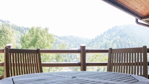 A wooden deck with a table and chairs, overlooking a forested valley. - Sterling One Bedroom Suite in Great location with Majestic Mountain Views 1 Condo by RedAwning (Park City)