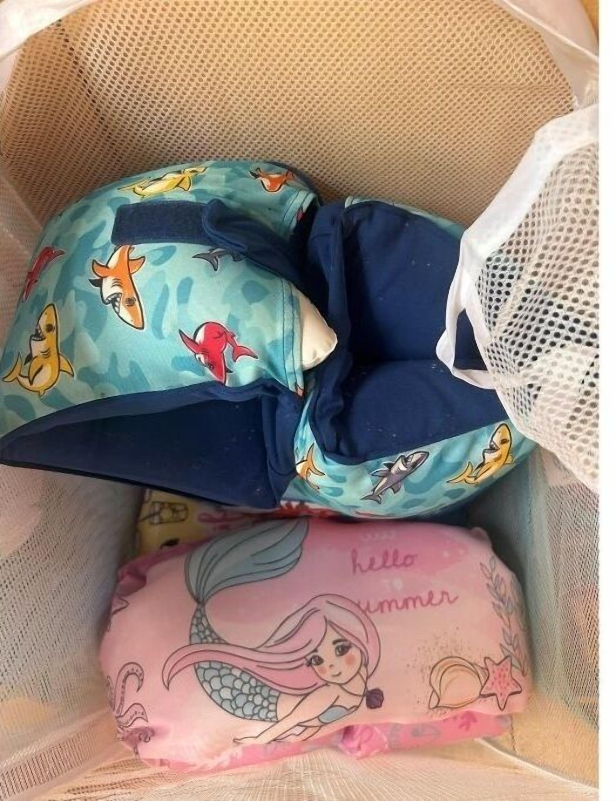A storage bin with a camouflage-patterned pillow and a mermaid-themed pillow.