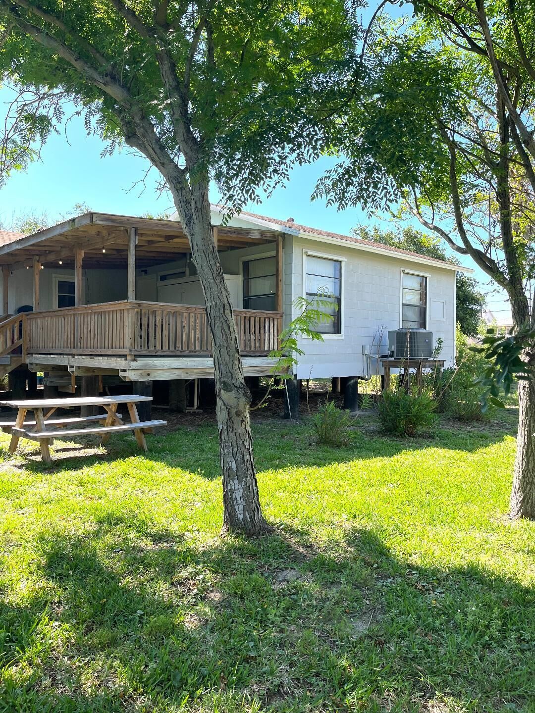 A single-story mobile home with a wooden deck and a covered porch.