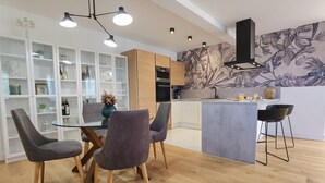 Una cocina moderna con armarios de madera, una isla central y un comedor con mesa y sillas de vidrio.