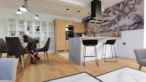 Una cocina moderna con armarios de madera, una isla central, taburetes de bar e iluminación colgante.