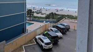 Ein Balkon mit Blick auf den Strand und geparkte Autos.