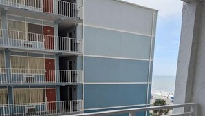Ein Balkon mit Meerblick, ein Gebäude mit blau-weißen Wänden und zwei Stühle.