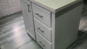 A kitchen with a white countertop, three drawers, and a dining area with a table and chairs. - Carnbee Cozy Cottage (Carnbee)