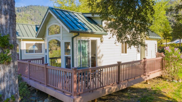 A cabin with a covered deck and a sliding glass door. - Strawhouse Resorts on the Beautiful Trinity River (Big Flat)
