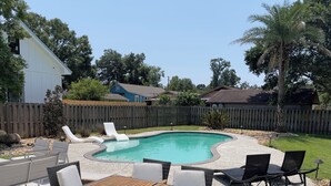 Ein Garten mit Schwimmbad, Gartenmöbeln und einer Holzterrasse.