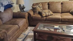 A living room with two brown leather sofas, a glass coffee table, and a patterned rug. - 4-Person Condo only a short walk to beach. (Destin)